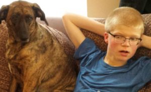 Teen with Smith-Kingsmore syndrome sitting with his dog