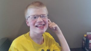 Teen with Smith-Kingsmore syndrome laughing with one finger in his ear