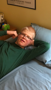 Teen with Smith-Kingsmore syndrome lying back on his bed in a thoughtful pose
