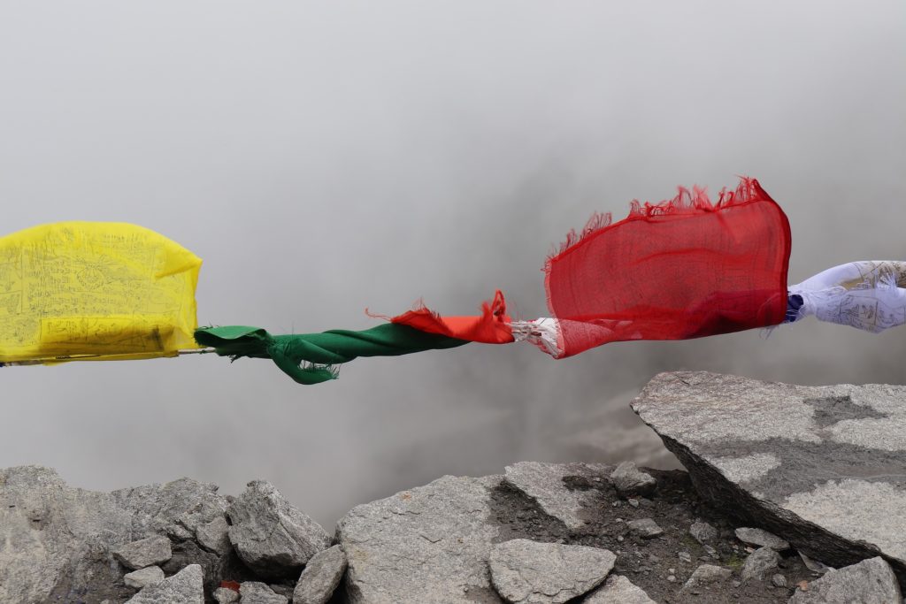 Colorful pieces of fabric flags tied together to make a rope above rocks