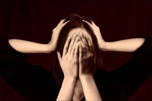 Stressed out woman with hands over her face and other hands on both sides of her head