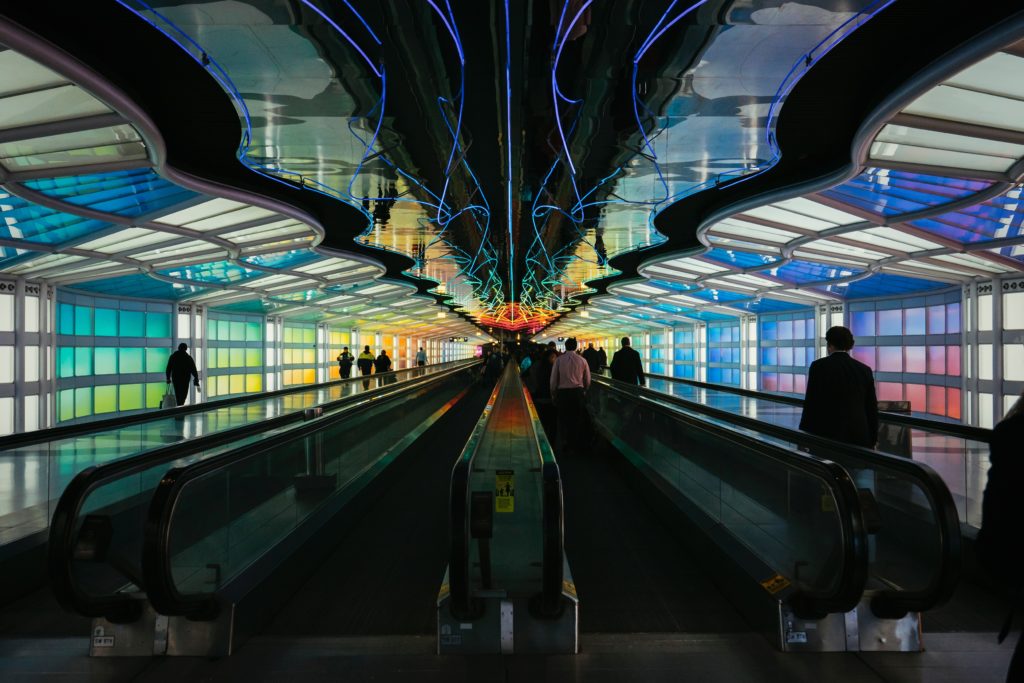 The inside of a dark pedestrian tunnel with colorful lights on the walls and ceiling