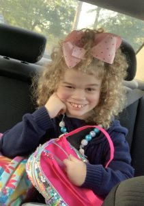 Curly haired girl with Smith-Kingsmore syndrome holding purse