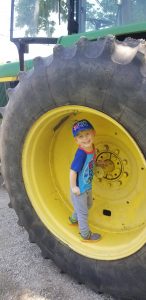 Boy with Smith-Kingsmore syndrome smiling, standing in giant tire