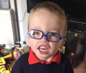 Boy with Smith-Kingsmore syndrome wearing blue glasses
